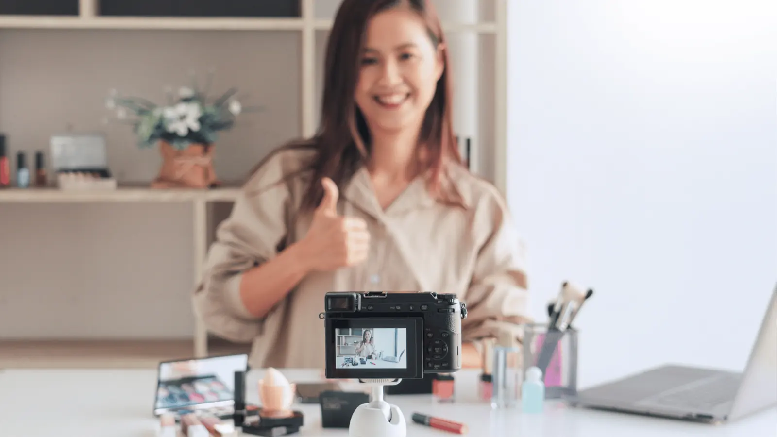 Smiling woman gives thumbs up while recording a makeup tutorial