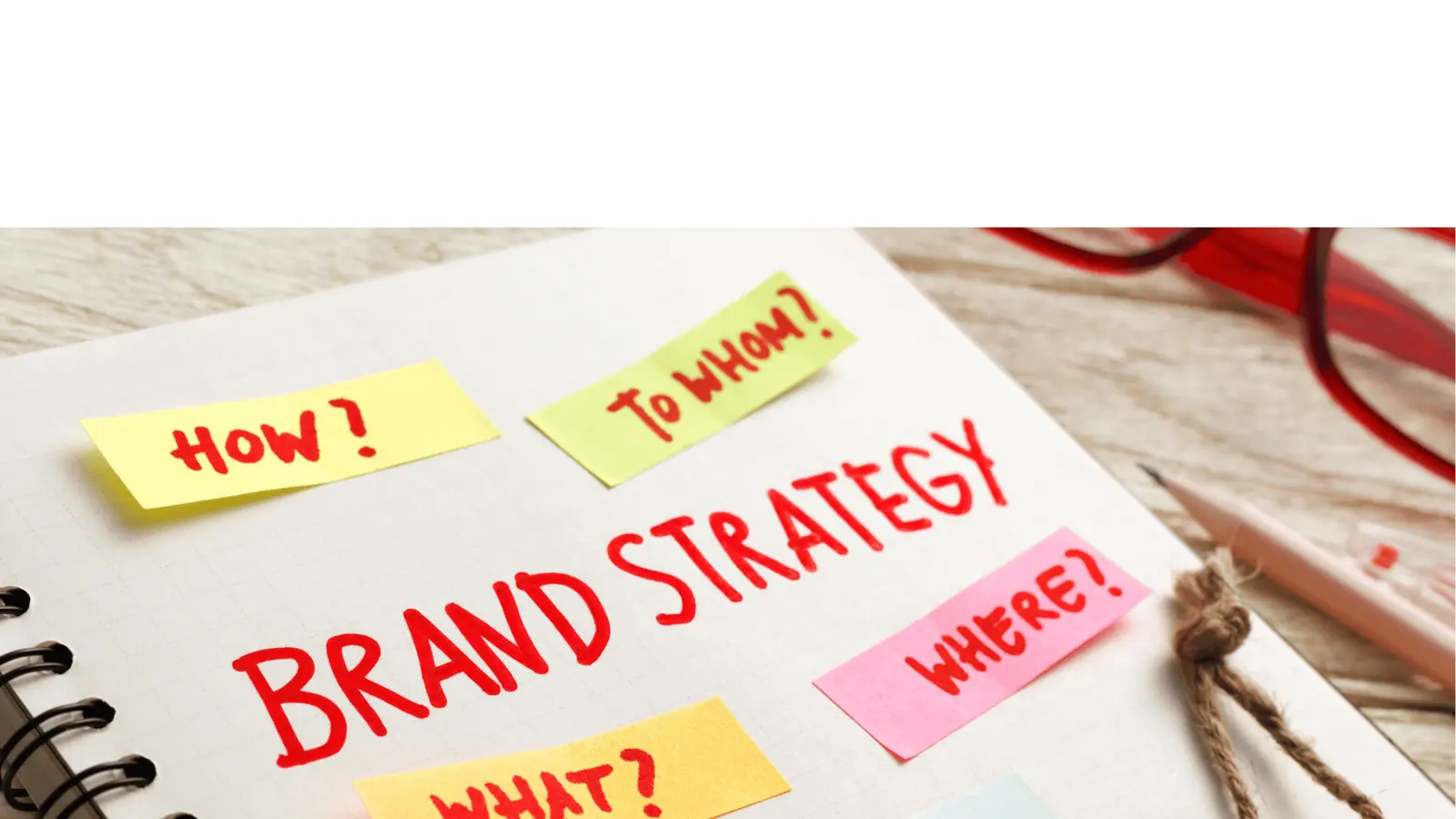 Notebook page reading BRAND STRATEGY with colorful sticky notes asking questions for inbox management