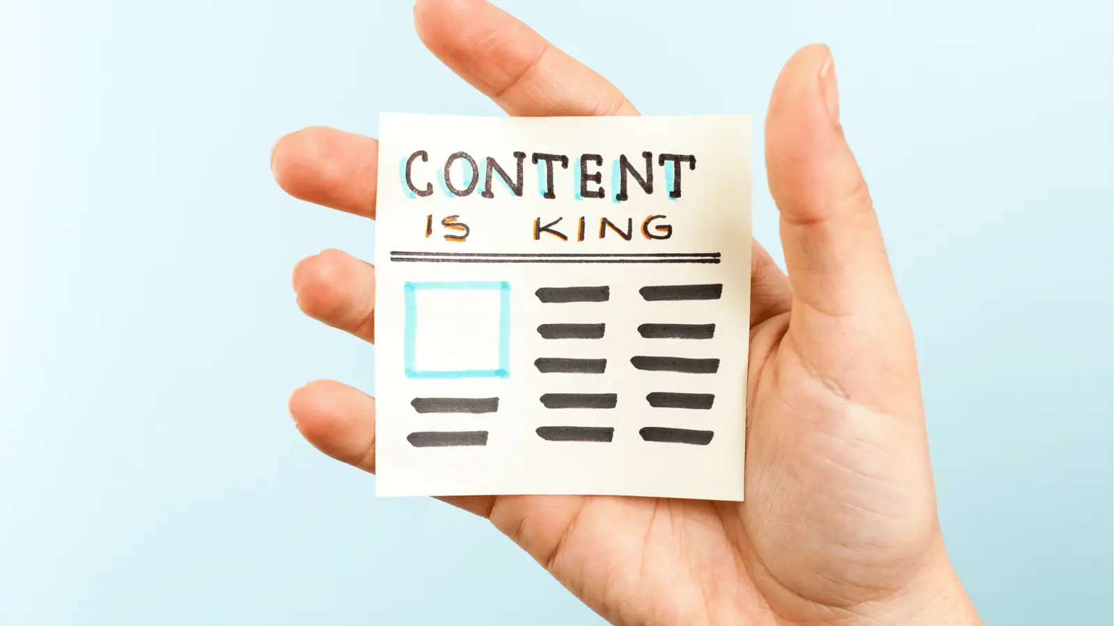 Hand holding sticky note reading 'Content is King' with drawn layout for scheduling
