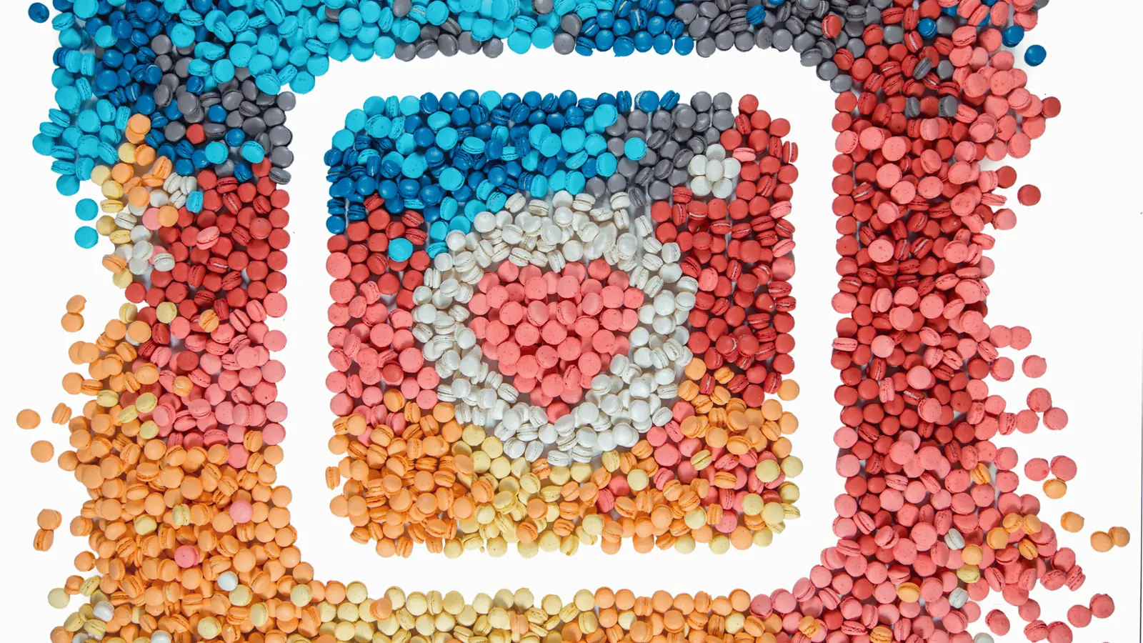 Top-down view of colorful macarons arranged as Instagram app icon on white