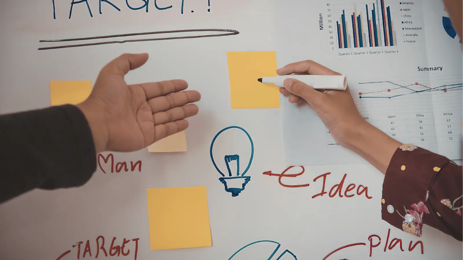 Two hands arranging sticky notes and drawings on a whiteboard for AI-assisted workflow