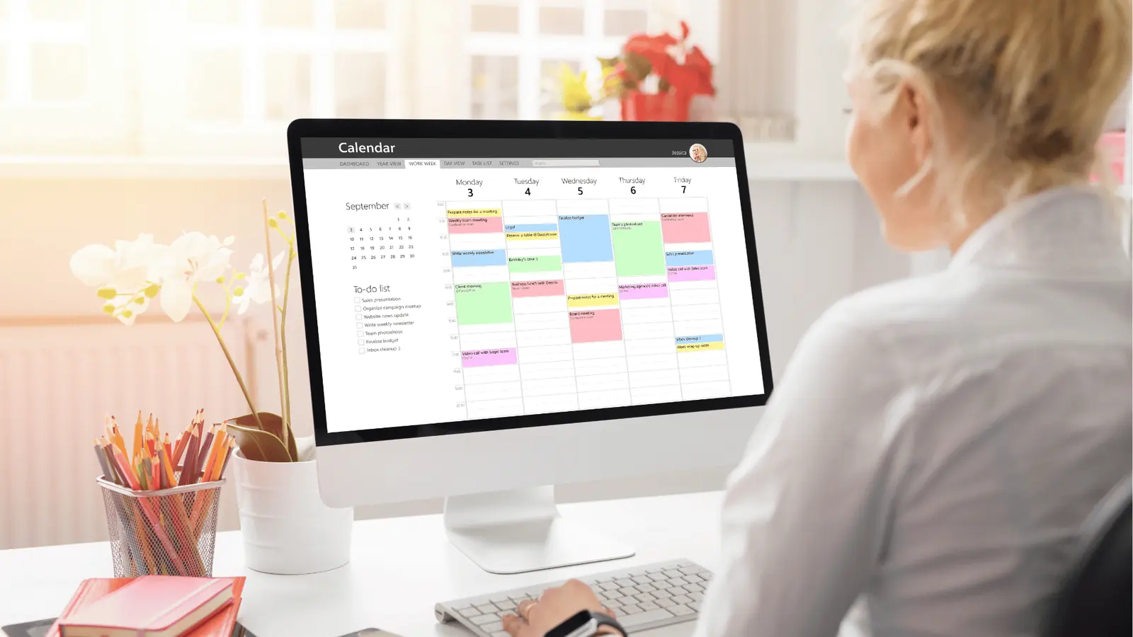 Woman at desk viewing a weekly calendar and to-do list on monitor for analytics
