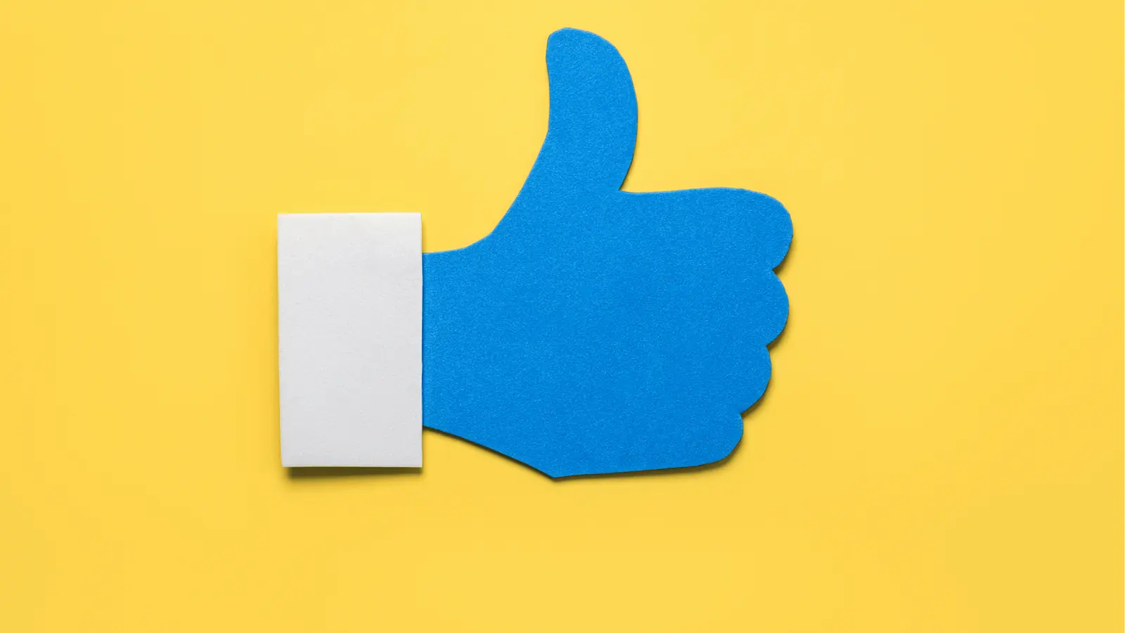 Blue thumbs-up cutout on yellow background with white cuff for approval workflow