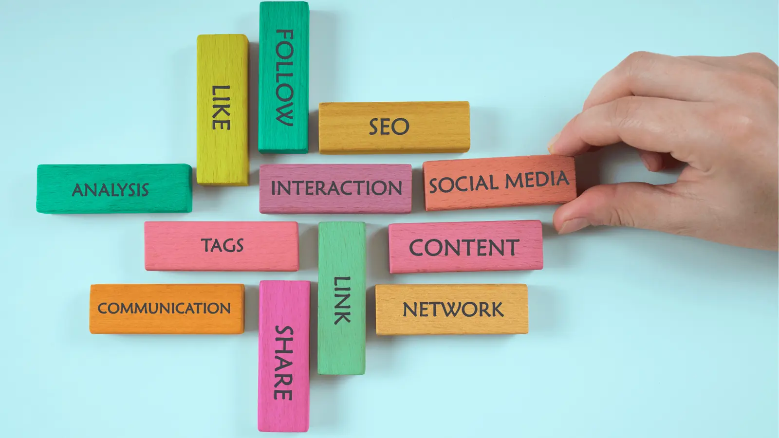 Hand arranging colorful wooden blocks labeled with social media marketing words for content calendar