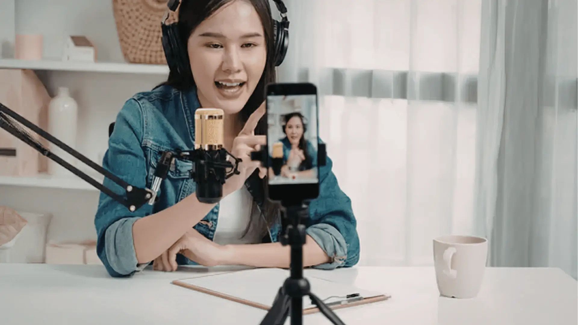 Woman recording a live video on smartphone with microphone and headphones for analytics
