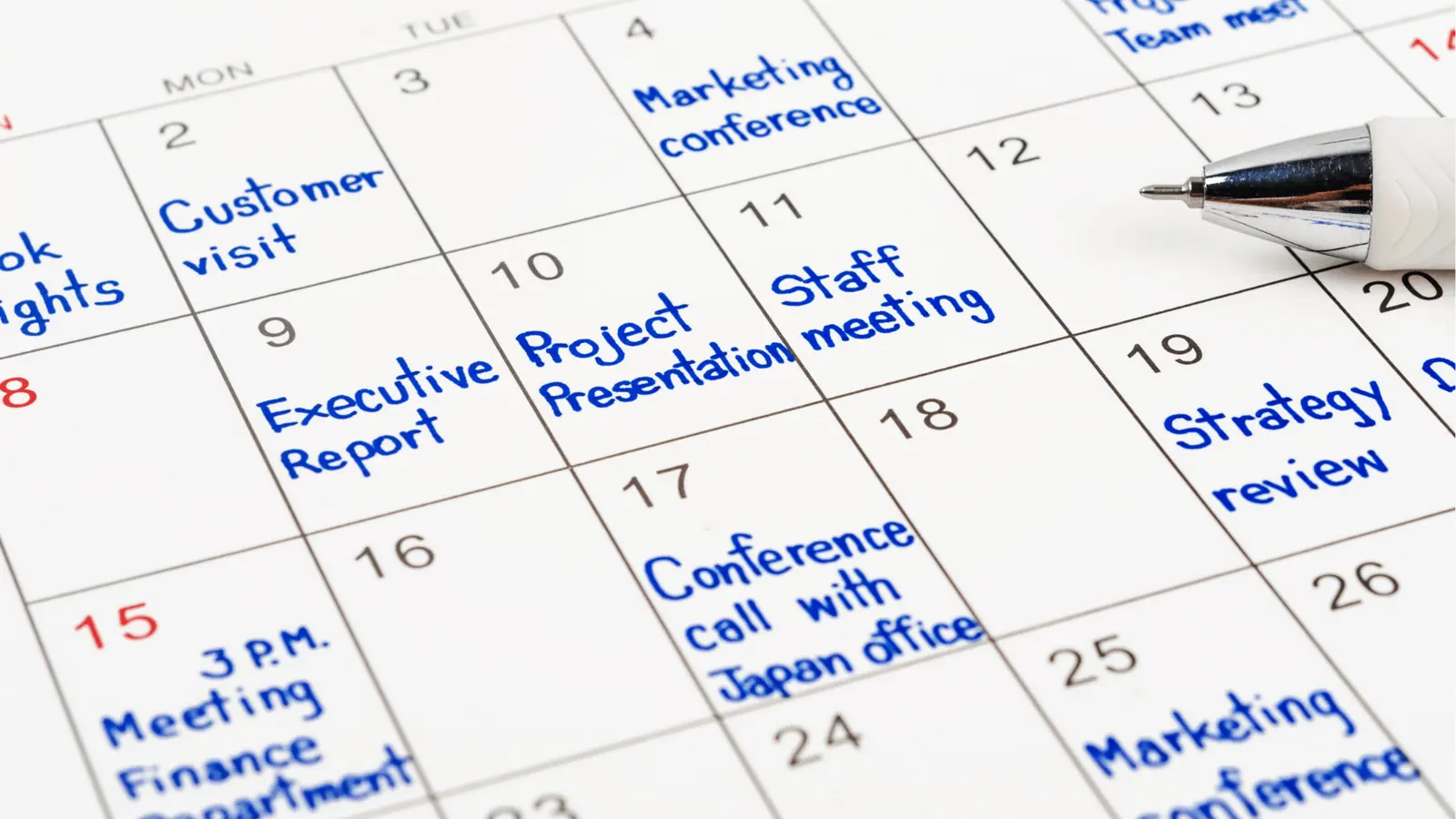 Close-up calendar page with handwritten blue appointment notes and pen for approval workflow