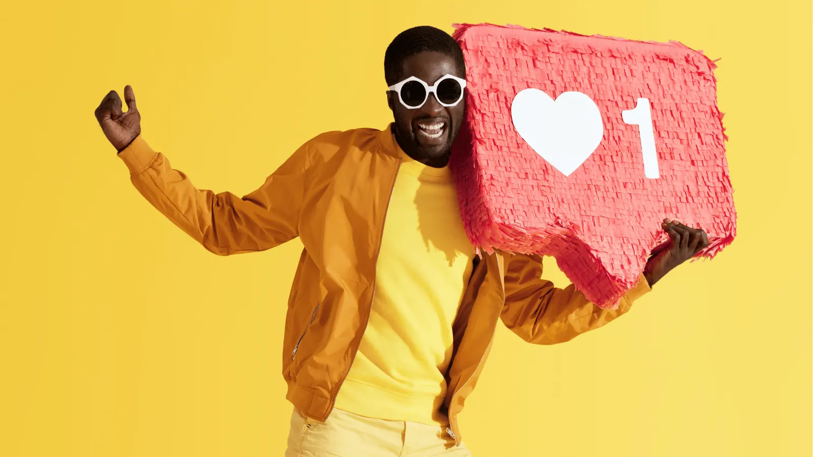 Smiling man wearing sunglasses holding a red like notification pinata for workflow