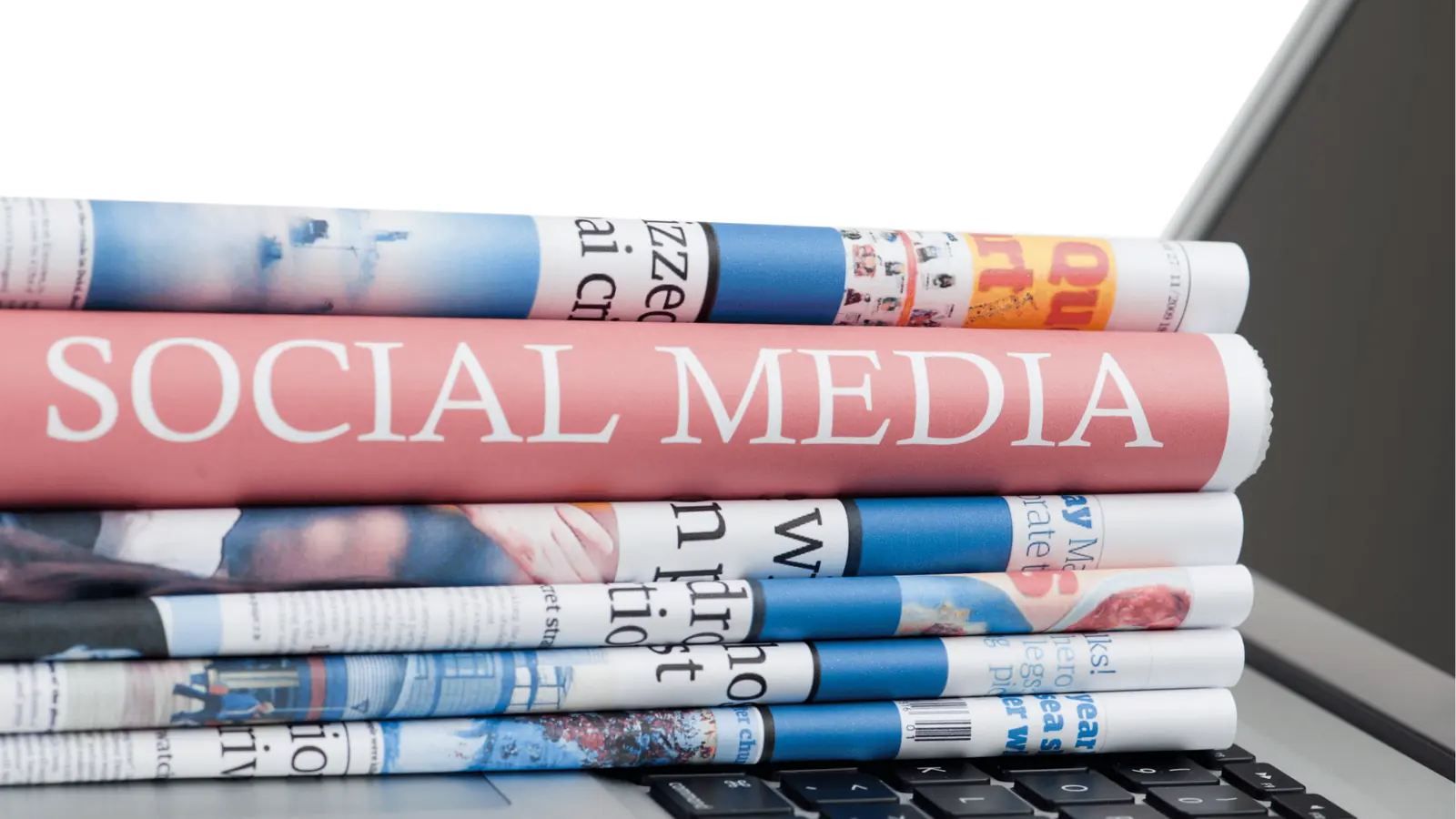 Rolled newspapers stacked on a laptop keyboard with 'SOCIAL MEDIA' headline for multi-brand management