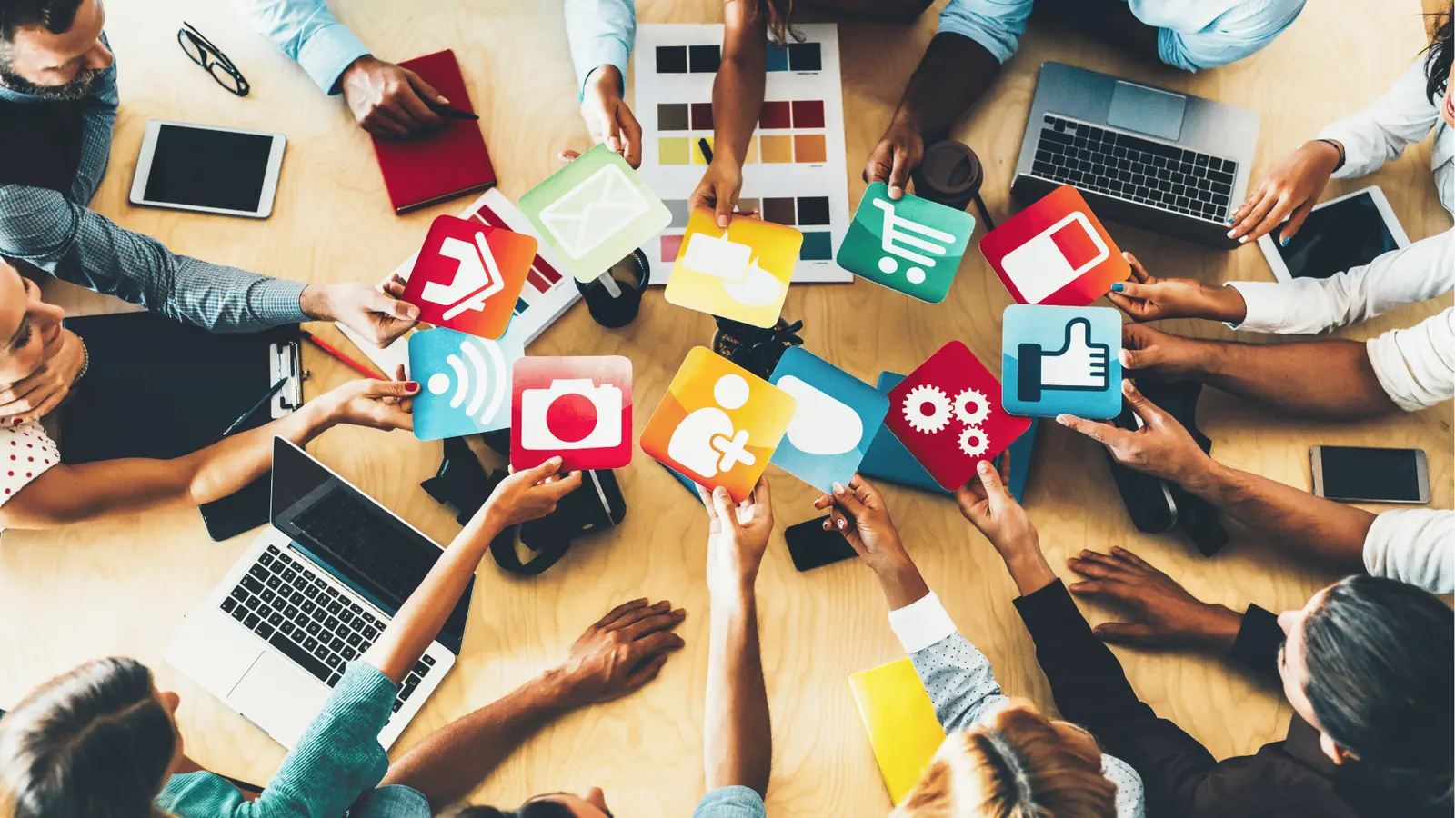 Overhead view of a team holding colorful social media and app icon cards for asset management