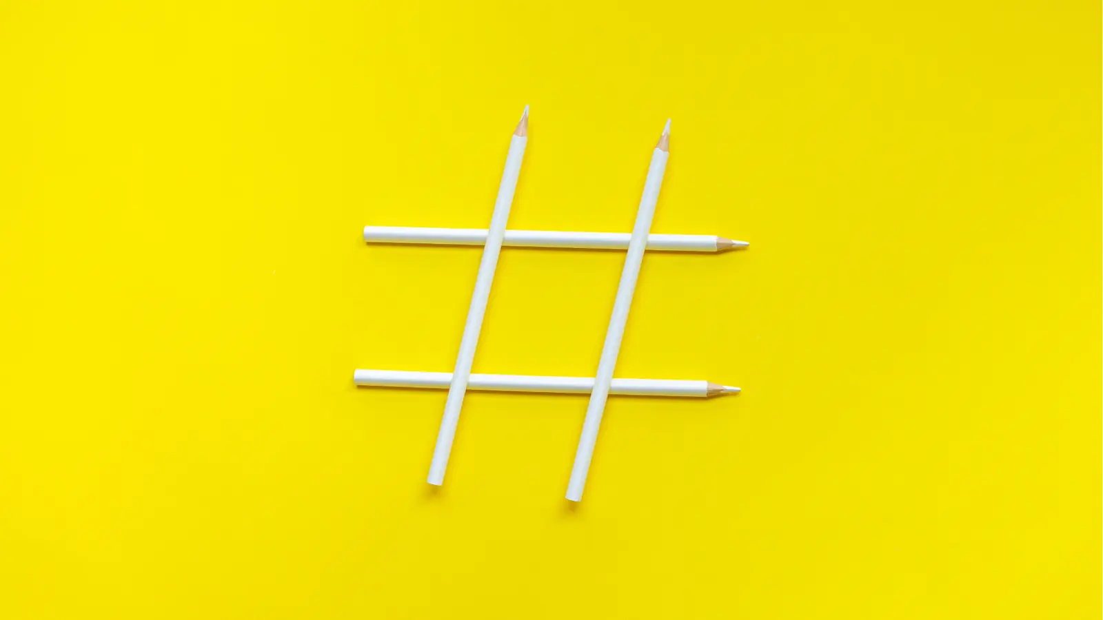 Four white pencils arranged as a hashtag on yellow background for multi-brand management